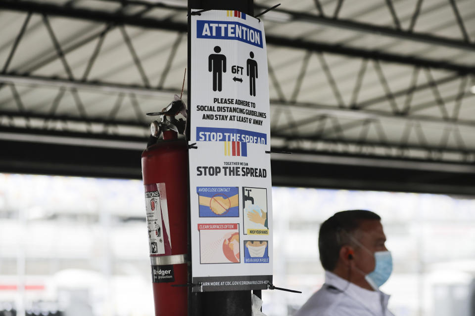 A sign reminding people of social distancing and safety measures because of the coronavirus is posted in the garage area before the NASCAR Xfinity series auto race Tuesday, May 19, 2020, in Darlington, S.C. (AP Photo/Brynn Anderson)