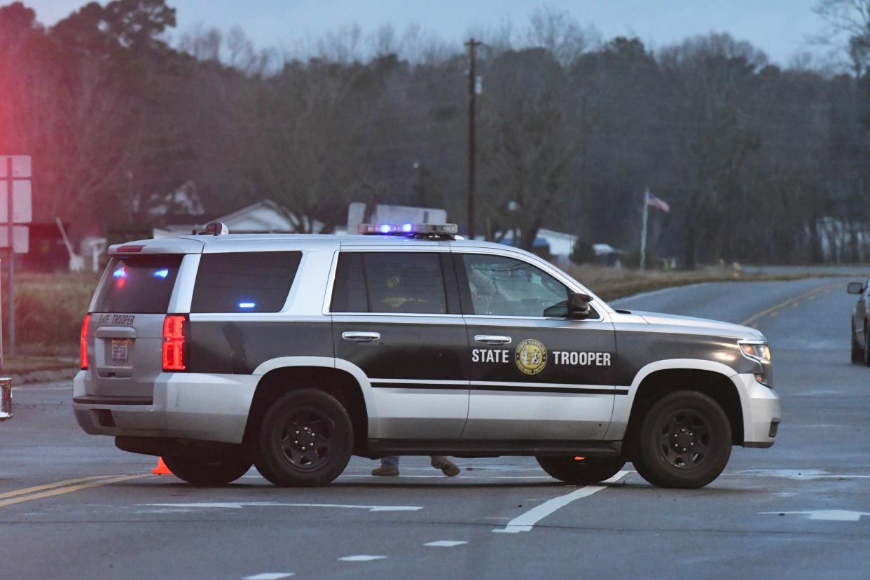 A State Trooper blocks an intersection as emergency crews gather at a staging area near Sunset Beach, N.C. on Tuesday, Feb. 16, 2021.