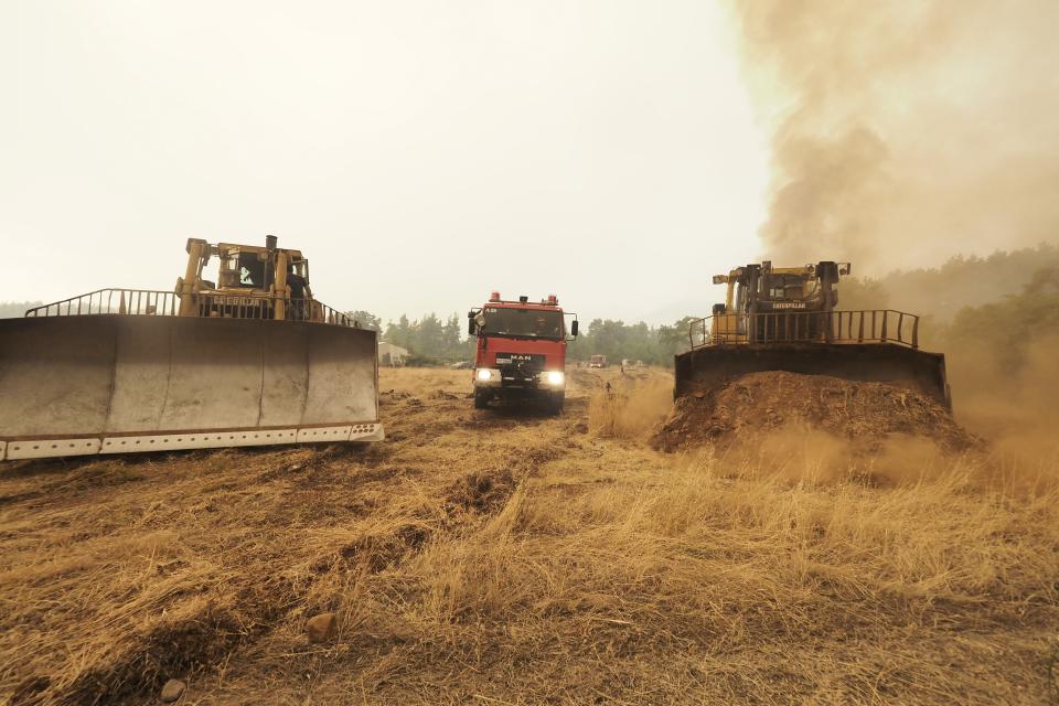 Bulldozers open fire break next to a forest during a wildfire near Kechries village on the island of Evia, about 144 kilometers (90 miles) north of Athens, Greece, Thursday, Aug. 5, 2021. Forest fires fueled by a protracted heat wave raged overnight and into Thursday in Greece, threatening the archaeological site at the birthplace of the modern Olympics and forcing the evacuation of dozens of villages. (AP Photo/Thodoris Nikolaou)