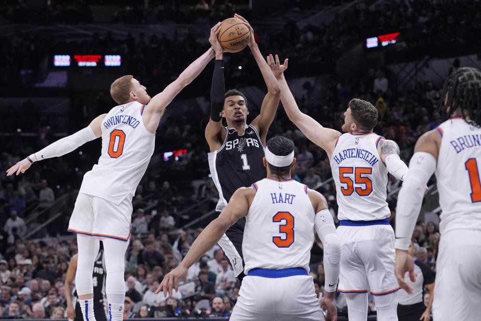 San Antonio Spurs center Victor Wembanyama (1) is defended by New York Knicks guard Donte DiVincenzo (0) and center Isaiah Hartenstein (55) during the second half of an NBA basketball game in San Antonio, Friday, March 29, 2024. (AP Photo/Eric Gay)