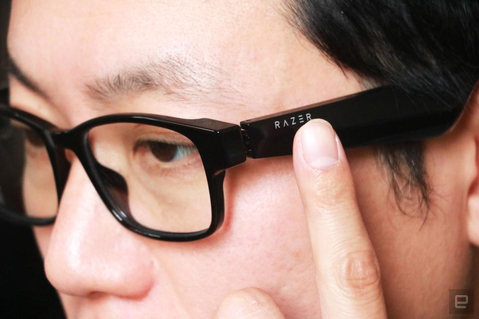 <p>Razer Anzu smart glasses review photo. Close up of the left side profile of a man wearing the Razer smart glasses with his left index finger touching the left arm right below the Razer logo.</p>
