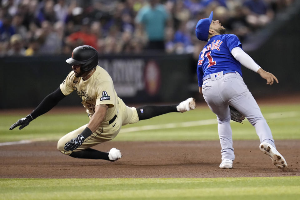 Arizona Diamondbacks' Tommy Pham, left, dives around Chicago Cubs third baseman Nick Madrigal, right, for a triple during the fourth inning of a baseball game Saturday, Sept. 16, 2023, in Phoenix. (AP Photo/Ross D. Franklin)