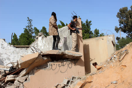 Members of the Libyan internationally recognised government forces look out from a destroyed building at Khallat Farjan area in Tripoli, Libya April 20, 2019. REUTERS/Ayman al-Sahili