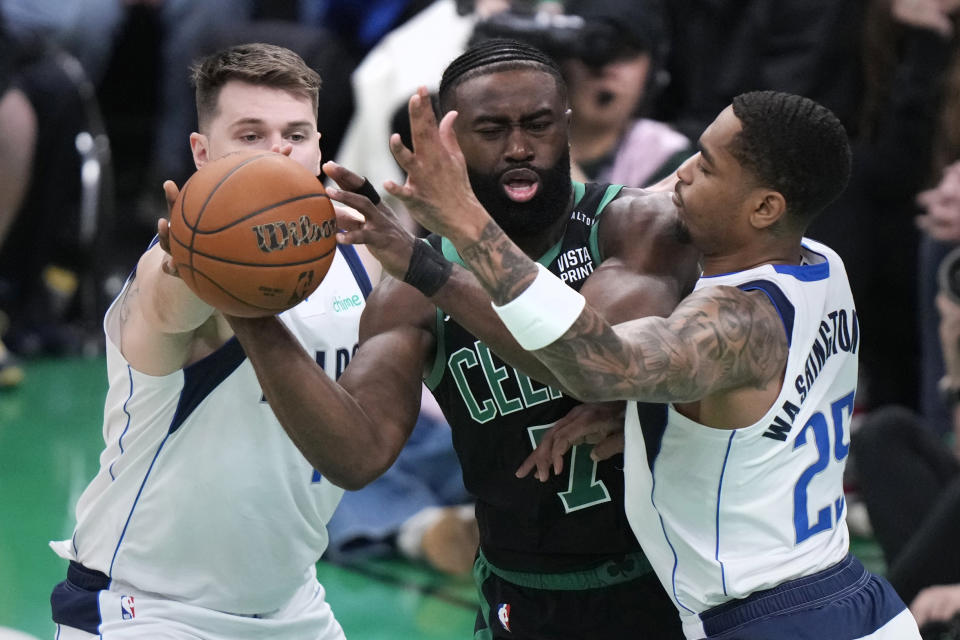 Boston Celtics guard Jaylen Brown, center, tries to pass while pressured by Dallas Mavericks forward P.J. Washington (25) and guard Luka Doncic, left, during the first half of Game 2 of the NBA Finals basketball series, Sunday, June 9, 2024, in Boston. (AP Photo/Steven Senne)