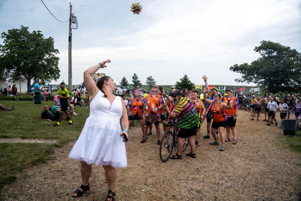 RAGBRAI rider Jamie Stacey throws the bouquet to friends after her wedding at the Iowa Craft Beer Tent on Tuesday, July 25, 2023, near Luther.