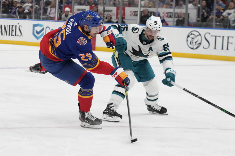 St. Louis Blues' Jordan Kyrou (25) shoots as San Jose Sharks' Erik Karlsson (65) defends during the second period of an NHL hockey game Thursday, March 9, 2023, in St. Louis. (AP Photo/Jeff Roberson)