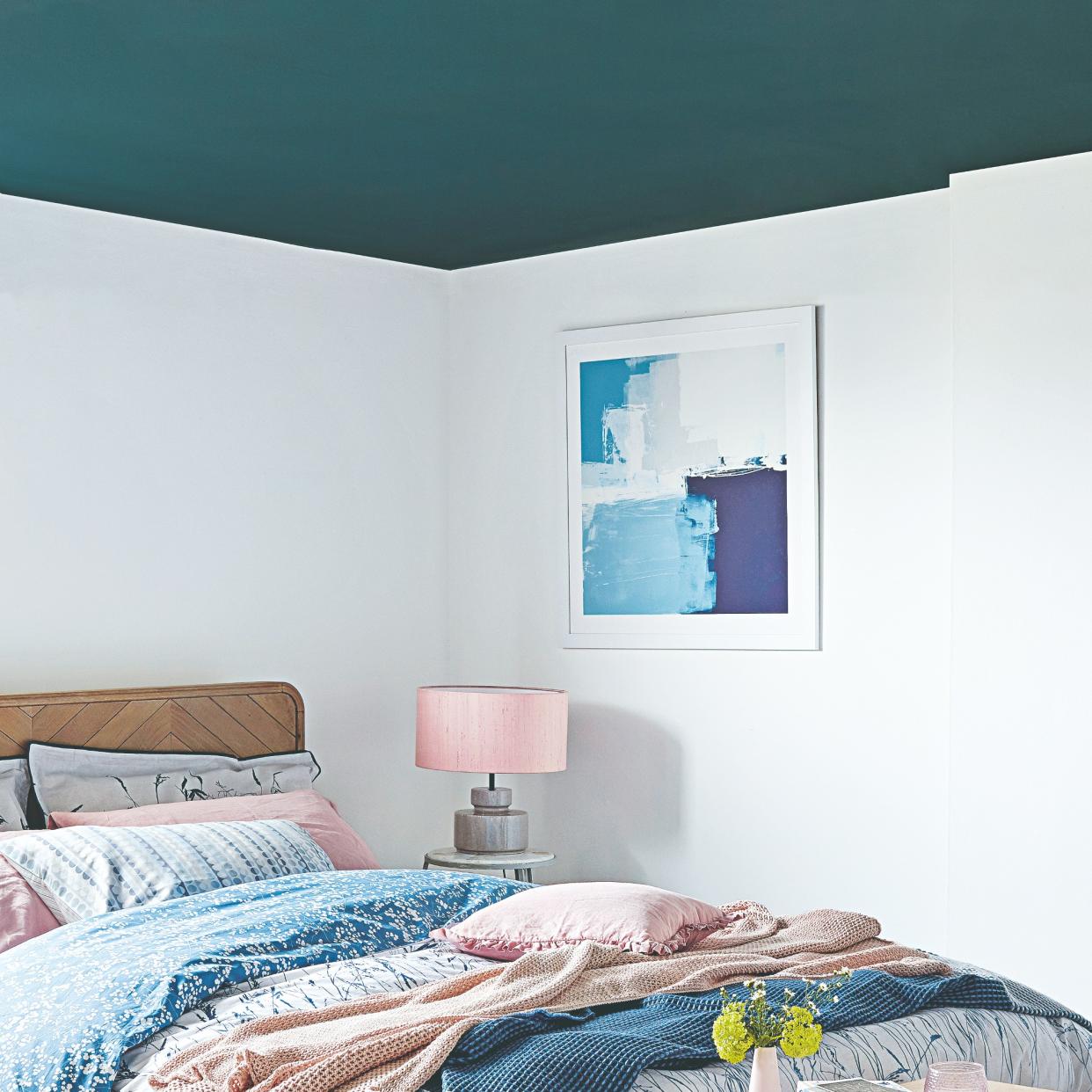  A bedroom with a contrasting blue painted ceiling. 