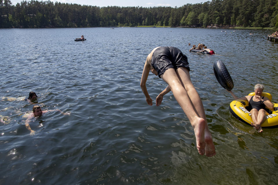 People enjoy the warm weather near a lake near Vilnius, Lithuania, Sunday, June 20, 2021. The hot weather continues in Lithuania as temperatures reached 33 degrees Celsius (91,40 degrees Fahrenheit). (AP Photo/Mindaugas Kulbis)