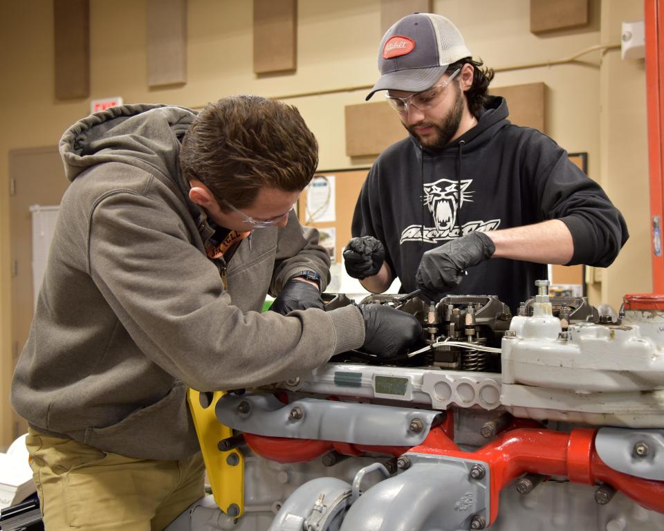 Portsmouth Naval Shipyard heavy mobile equipment mechanics Alex Cancelada and Hayden Beaulieu check the clearances on crane engine valves in the shop learning center.
