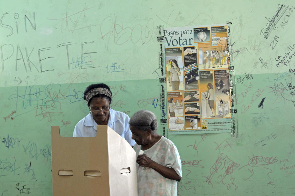 An elderly woman, right, gets help by a relative to mark her ballot during the presidential election in Santo Domingo, Dominican Republic, Sunday May 20, 2012. (AP Photo/Manuel Diaz)