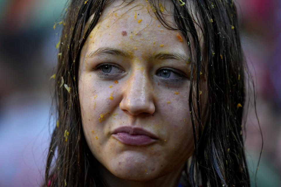 A girl reacts as her face is covered with orange juice during the 'Battle of the Oranges" where people pelt each other with oranges as part of Carnival celebrations in the northern Italian Piedmont town of Ivrea, Italy, Tuesday, Feb. 13, 2024. (AP Photo/Antonio Calanni)