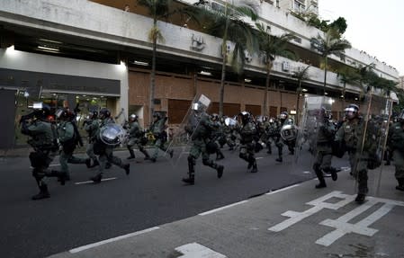 Police officers run during a demonstration by anti-government protesters in Sha Tin