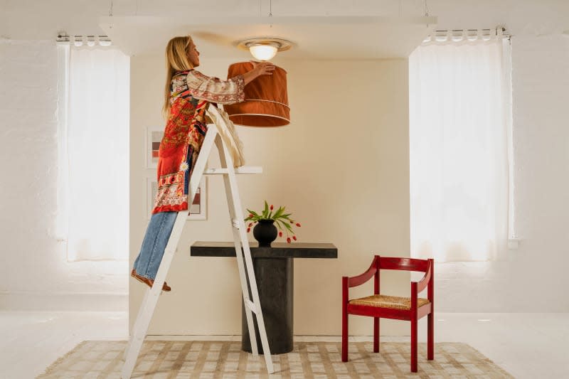 someone installing a tulip lamp shade over their home ceiling light fixture