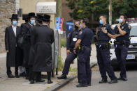 Members of the Orthodox Jewish community speak with NYPD officers, Wednesday, Oct. 7, 2020, in the Borough Park neighborhood of the Brooklyn borough of New York. Gov. Andrew Cuomo moved to reinstate restrictions on businesses, houses of worship and schools in and near areas where coronavirus cases are spiking. Many neighborhoods that stand to be affected are home to large enclaves of Orthodox Jews. (AP Photo/John Minchillo)