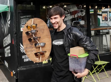 Havrylenko, CEO of innovative OCHIS COFFEE eyewear brand, holds eco-friendly sunglasses as he picks up coffee waste in a cafe in Kiev