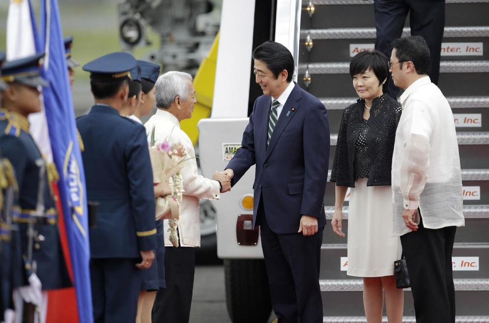 Japanese Prime Minister Shinzo Abe, third from right, shakes hands with Philippine Foreign Affairs Secretary Perfecto Yasay as his wife Akie, second from right, stands behind him upon arrival at Manila's airport, Philippines, Thursday, Jan. 12, 2017. Abe is in the country for a two-day official visit. (AP Photo/Aaron Favila)