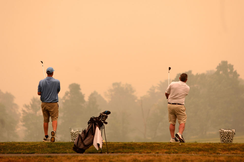 Golfers watch their shots at the driving range at Valley Country Club in Sugarloaf, Pa., as smoke from wildfires in Canada fill the air, on June 7, 2023.<span class="copyright">John Haeger—Standard-Speaker/AP</span>