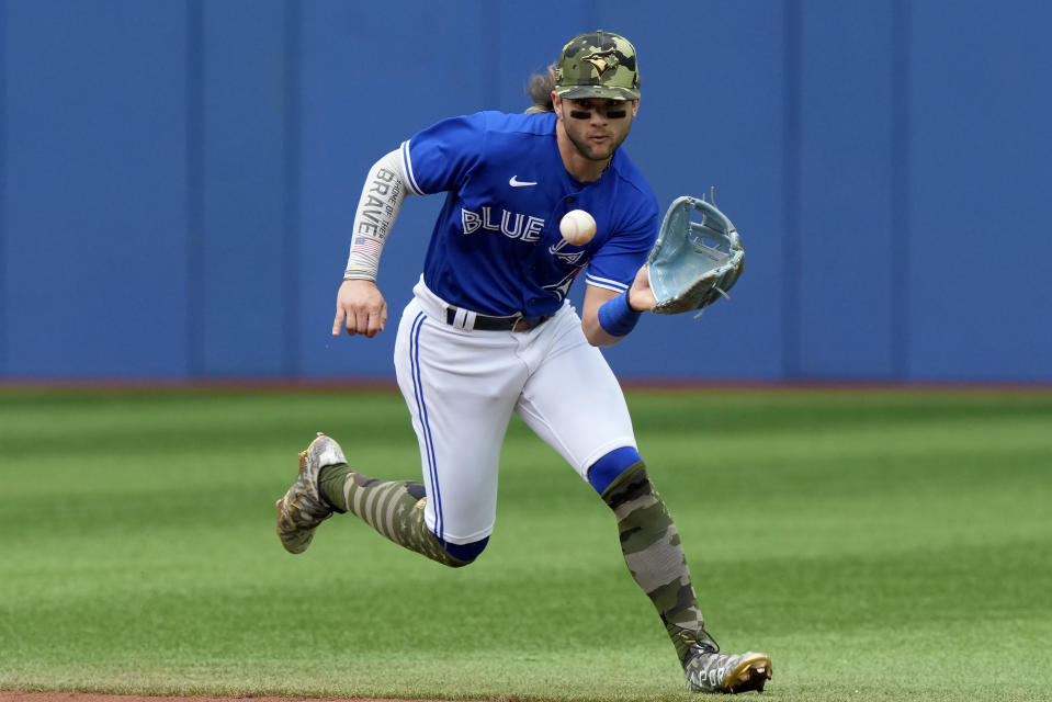 Toronto Blue Jays shortstop Bo Bichette (11) runs down a ground ball hit by Cincinnati Reds third baseman Mike Moustakas during the fifth inning of a baseball game in Toronto, Saturday, May 21, 2022. (Frank Gunn/The Canadian Press via AP)