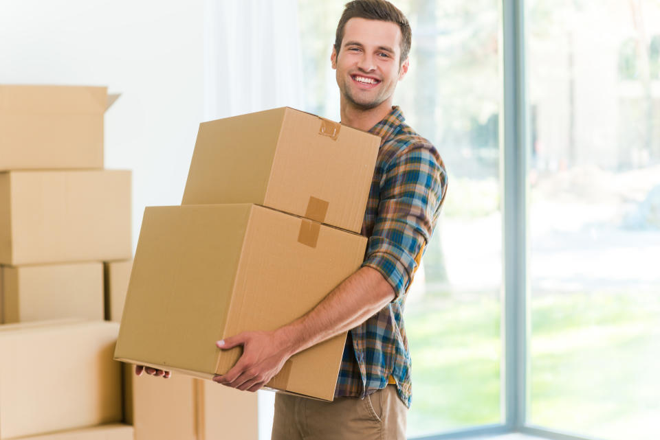 Smiling young man holding moving boxes