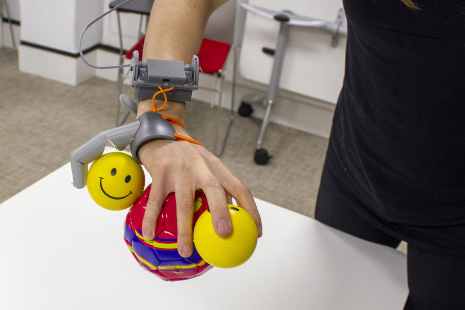 Participants used the 'Third Thumb' to complete training tasks including holding multiple balls with one hand. (SWNS)