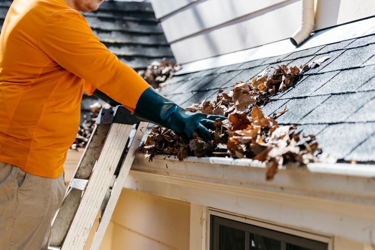 man removing leaves from gutters