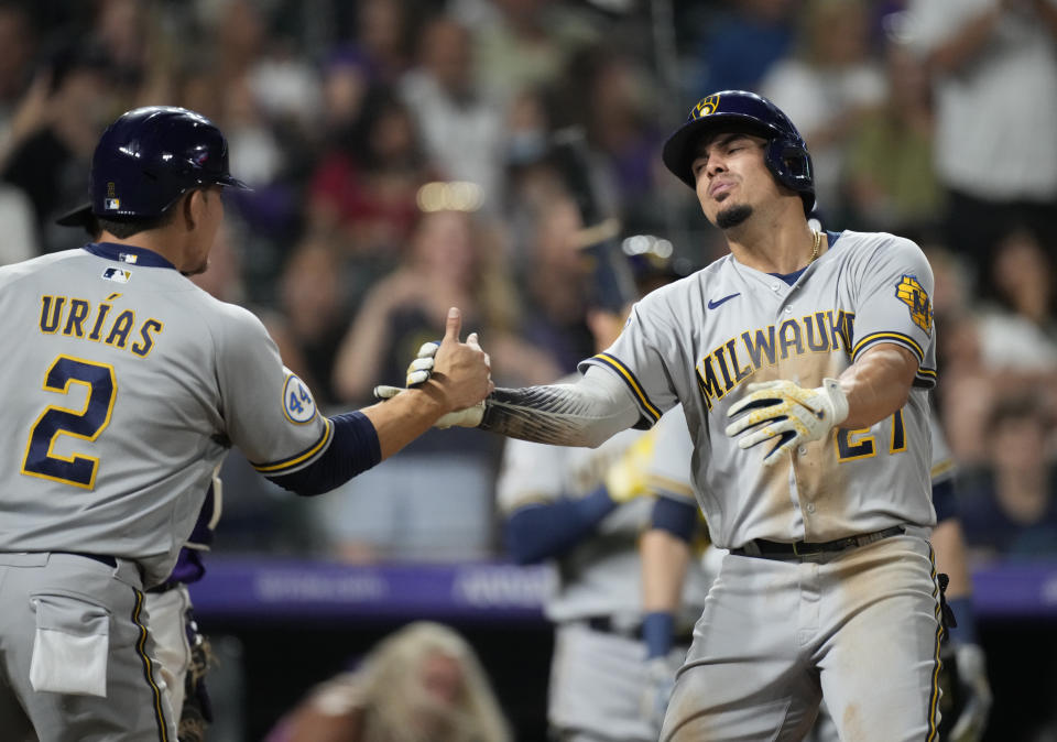 Milwaukee Brewers' Luis Urias, left, congratulates Willy Adames, who crosses home plate after hitting a two-run home run off Colorado Rockies relief pitcher Tyler Kinley during the ninth inning of a baseball game Saturday, June 19, 2021, in Denver. (AP Photo/David Zalubowski)