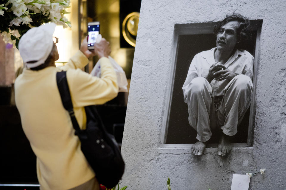 In this Sept. 6, 2019 photo, a man takes a photo of a photograph of the late Mexican painter Francisco Toledo during a memorial at the Bellas Artes Palace in Mexico City. Toledo, who was well-known and respected in Mexico both for his art and his activism, has died, the country's president announced late Thursday. (AP Photo/Eduardo Verdugo)