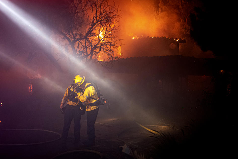 Firefighters recoil from smoke and heat from a fully engulfed house on Jolette Way in Granada Hills North, Calif., early Friday morning, Oct. 11, 2019. (Photo: David Crane/The Orange County Register via AP)