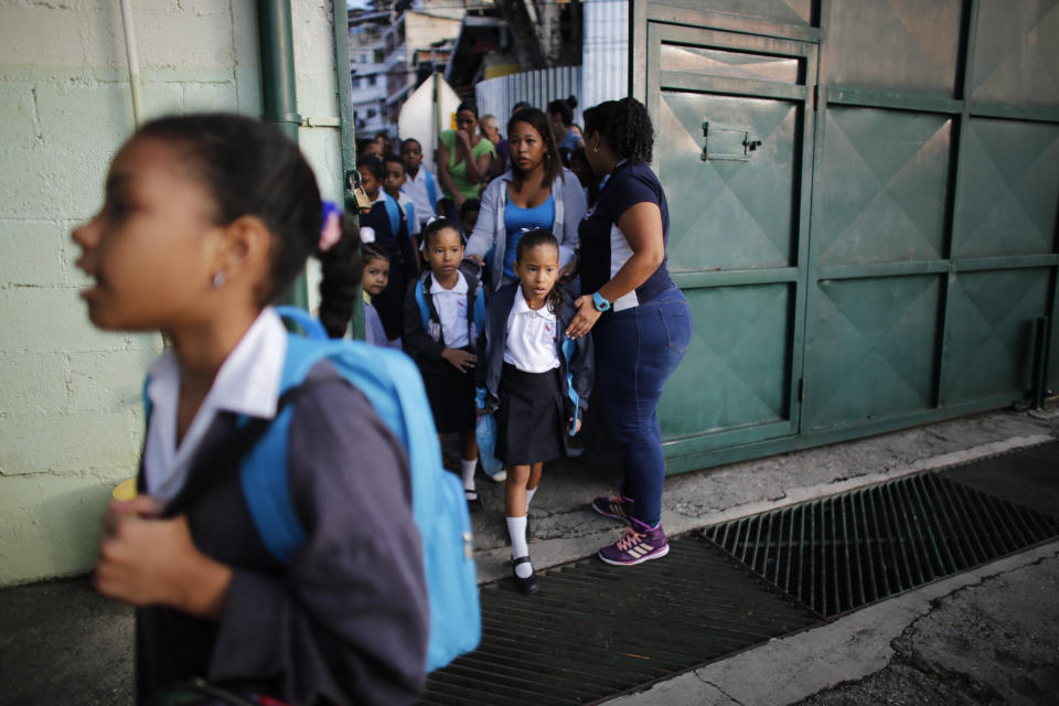 In this Oct. 2, 2019 photo, children enter school on their first day of class at the Jerman Ubaldo Lira public school in Caracas, Venezuela. Principal Erika Tortosa said that she has trouble finding enough teachers, who endure the same hardships that drive away the students' families. (AP Photo/Ariana Cubillos)