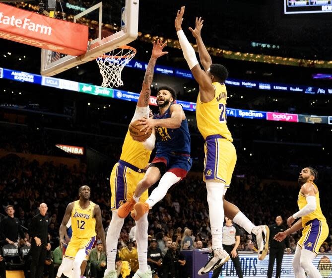 LOS ANGELES, CA - APRIL 25, 2024: Denver Nuggets guard Jamal Murray (27) splits defenders Los Angeles Lakers forward Anthony Davis (3) and Los Angeles Lakers forward Rui Hachimura (28) to make a pass under the basket in the fourth quarter of Denver's Game 3 win in the first round of the NBA playoffs at Crypto.com Arena on April 25, 2024 in Los Angeles, CA.(Gina Ferazzi / Los Angeles Times)