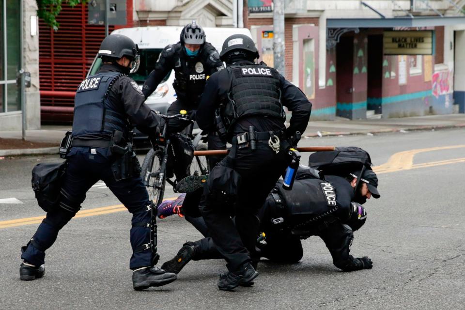 Police officers tackle a demonstrator to the floor at Seattle's CHOP zone, where Independent reporter Andrew Buncombe was arrested (AFP via Getty)