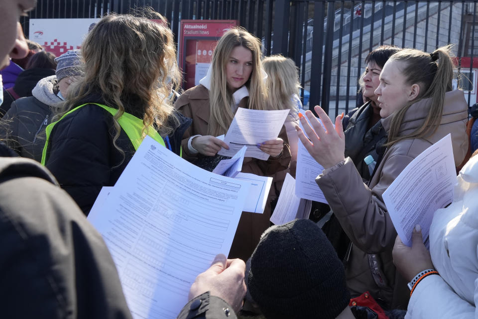 Ukrainian refugees talk near a special application point at the National Stadium in Warsaw, Poland, on Saturday, March 19, 2022. Hundreds of refugees from Ukraine waiting in line to apply for Polish ID numbers that will entitle them to work, free health care and education. (AP Photo/Czarek Sokolowski)