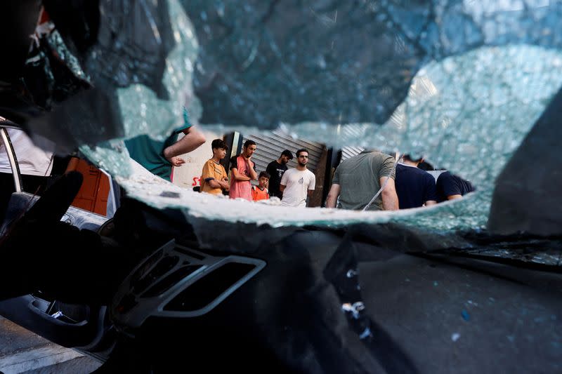 Un grupo de palestinos vistos a través del parabrisas roto de un coche en el lugar de un ataque israelí, en pleno conflicto entre Israel y el grupo islamista palestino Hamás, en Khan Younis