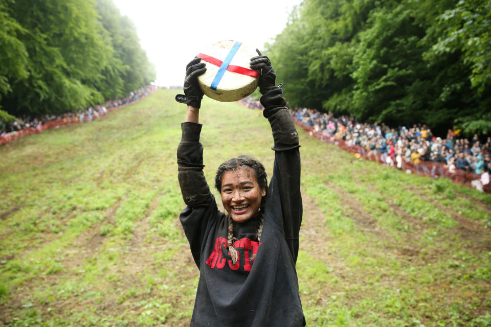 GLOUCESTER, ENGLAND - JUNE 05: Abby Lampe from North Carolina celebrates her win with the cheese in the woman's race on June 05, 2022 in Gloucester, England. The Cooper's Hill Cheese-Rolling and Wake annual event returns this year after a break during the Covid pandemic. It is held on the Spring Bank Holiday at Cooper's Hill, near Gloucester and this year it happens to coincide with the Queen's Platinum Jubilee. Participants race down the 200-yard-long hill after a 3.6kg round of Double Gloucester cheese. (Photo by Cameron Smith/Getty Images)
