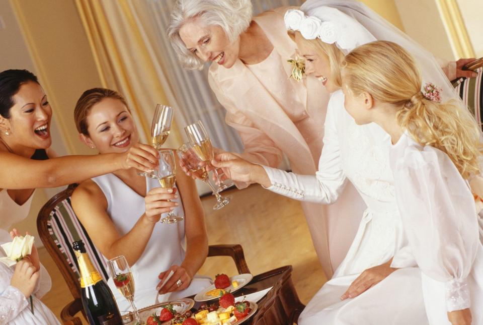 three women, bride and a young girl toasting with champagne