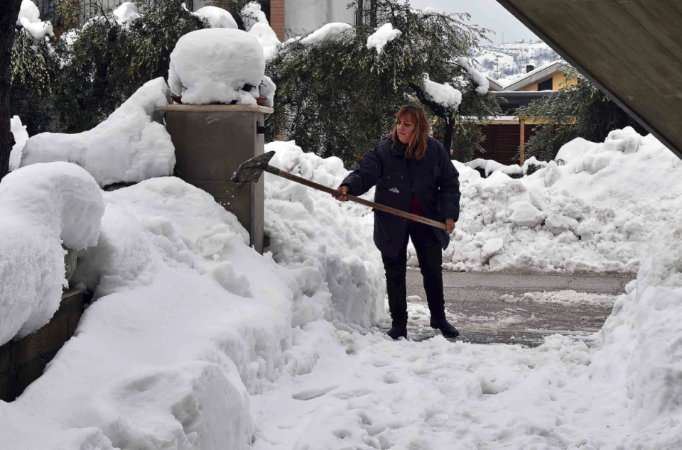 A local resident attempts to clear her drive in the aftermath of the avalanche (Picture: Reuters)