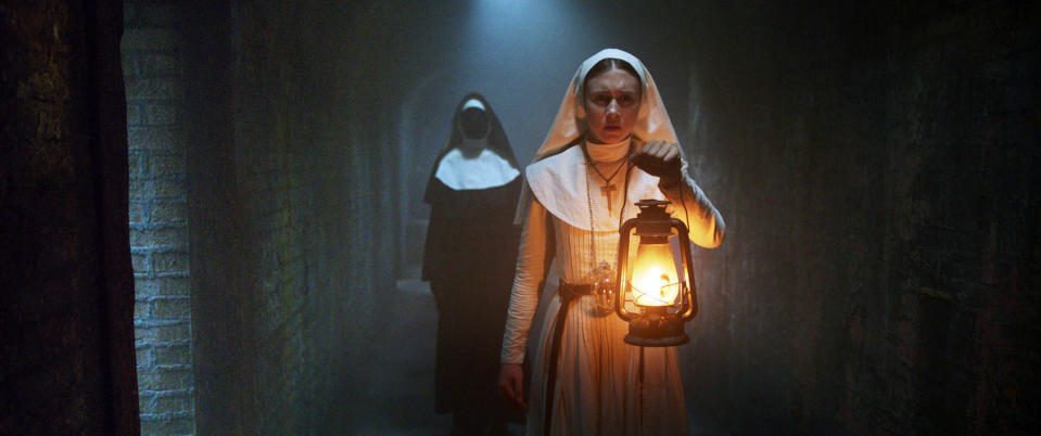 A young nun holding a lantern with a nun with no face trailing behind her