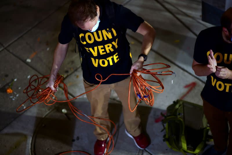 Activists wearing "COUNT EVERY VOTE" t-shirts coil electrical cord after a street dance party across the street from where votes are being counted in Philadelphia