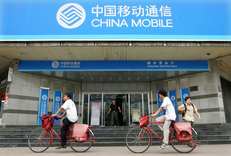 FILE PHOTO: FILE PHOTO: Chinese cyclists pedal past China Mobile office in Beijing.