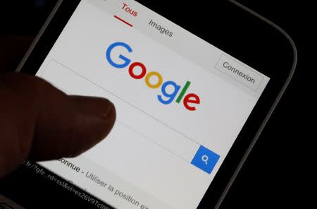 FILE PHOTO - A man holds his smartphone which displays the Google home page, in this picture illustration taken in Bordeaux, Southwestern France, August 22, 2016. REUTERS/Regis Duvignau