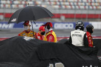 Driver Joey Logano, left, stands with an umbrella during a rain delay at a NASCAR Cup Series auto race at Charlotte Motor Speedway Sunday, May 24, 2020, in Concord, N.C. (AP Photo/Gerry Broome)