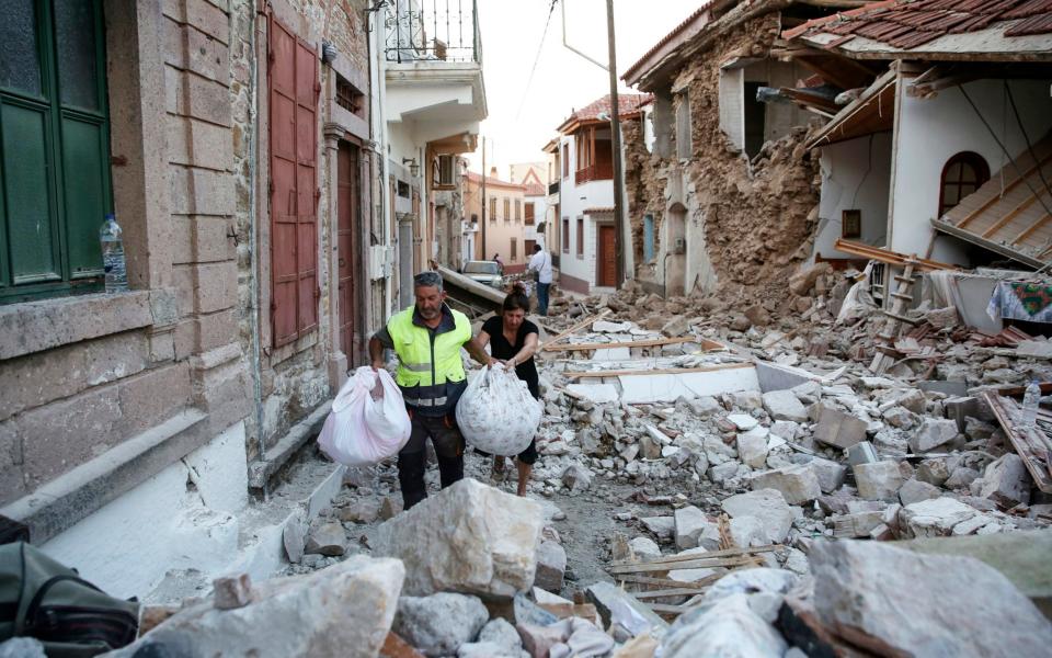 People carry their belongings amidst the rubble of collapsed houses in the village of Vrissas, following a strong earthquake that struck the island of Lesbos, 12 June 2017. - Credit: EPA