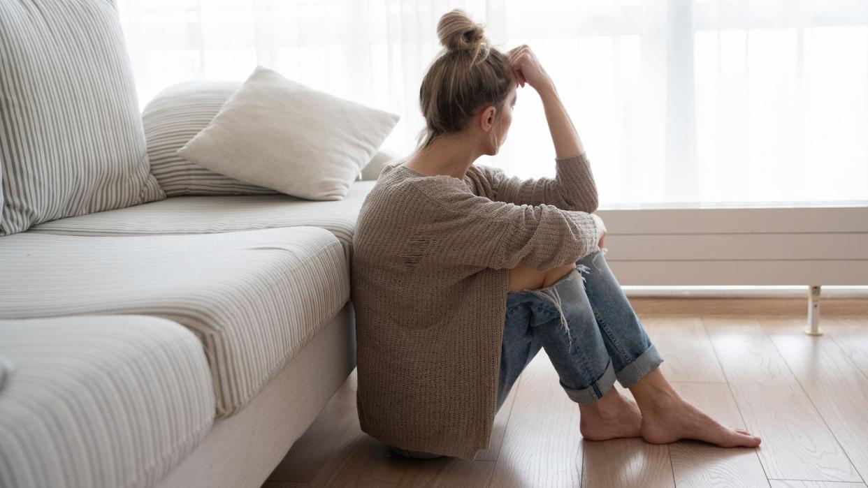 mujer deprimida sentada en el suelo