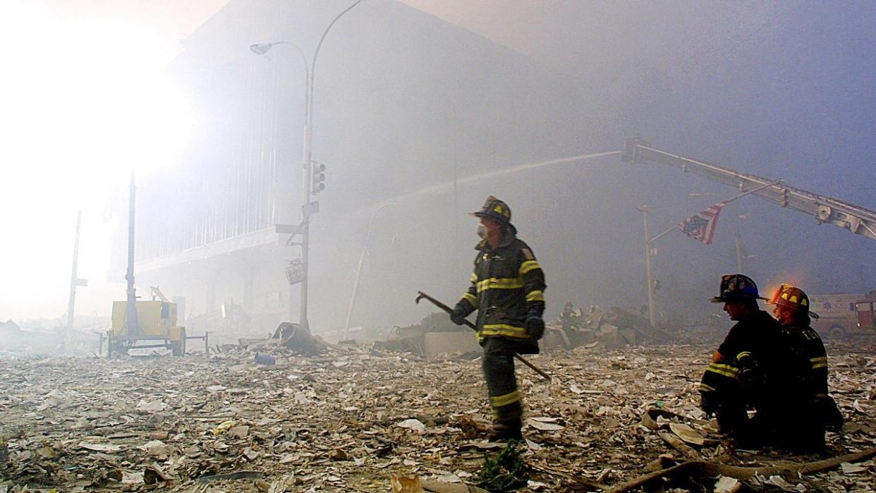 A firefighter walks through the rubble of the World Trade Center's twin towers as an American flag hangs from a traffic light on September 11, 2001, in New York City. Two planes controlled by hijackers crashed into the two buildings, destroying both.