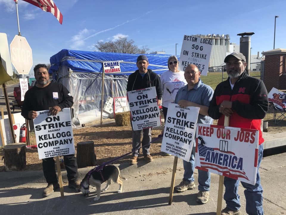 FILE - Striking Kellogg's workers Michael Rodarte, Sue Griffin, Michael Elliott, Eric Bates and Mark Gonzalez stand outside the Omaha, Neb., cereal plant on, Dec. 2, 2021. Kellogg's has reached a new tentative agreement on Thursday, Dec. 16, 2021, with its 1,400 striking cereal plant workers that could bring an end to the strike that began Oct. 5. Members of the Bakery, Confectionary, Tobacco Workers and Grain Millers International Union will vote on the new offer that includes cost-of-living adjustments and a $1.10 per hour raise for all employees on Sunday, Dec. 19. Last week, the union overwhelmingly rejected a previous offer from the Battle Creek, Michigan-based company. (AP Photo/Josh Funk, File)