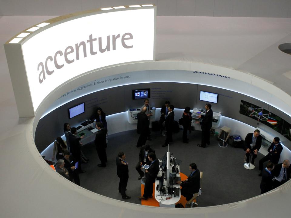 FILE PHOTO: Visitors look at devices at Accenture stand at the Mobile World Congress in Barcelona, February 26, 2013.    REUTERS/Albert Gea