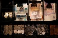 Pound Sterling notes and change are seen inside a cash resgister in a coffee shop in Manchester