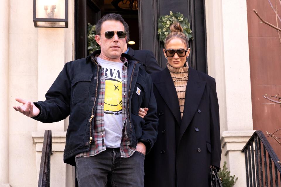 Ben Affleck and Jennifer Lopez step out. Ben wears a Nirvana t-shirt, plaid flannel, and jacket; Jennifer wears a striped turtleneck and long black coat