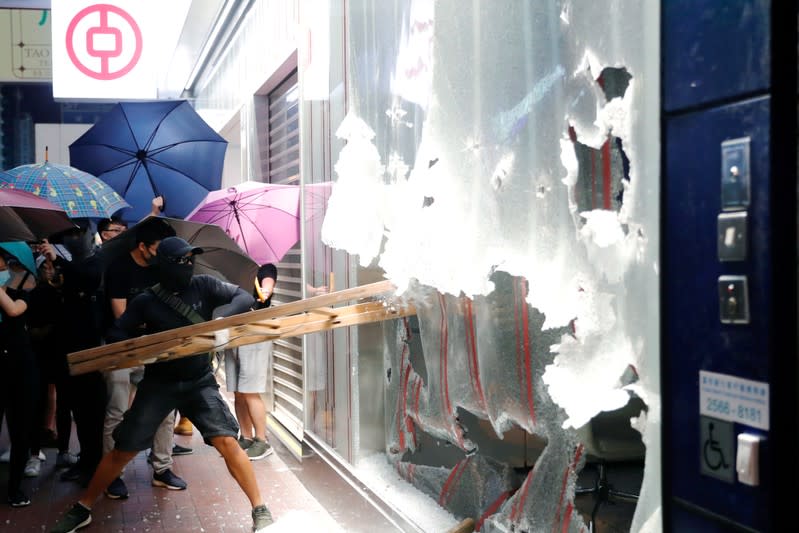 FILE PHOTO: An anti-government protester wearing a mask smashes glass at a Bank of China branch during a demonstration after a government ban on face masks under emergency law, at Mong Kok, in Hong Kong