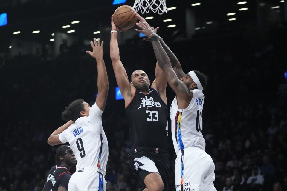 Los Angeles Clippers' Nicolas Batum (33) is defended by Brooklyn Nets' Dru Smith (9) and Royce O'Neale (00) during the second half of an NBA basketball game, Monday, Feb. 6, 2023, in New York. The Clippers won 124-116. (AP Photo/Frank Franklin II)